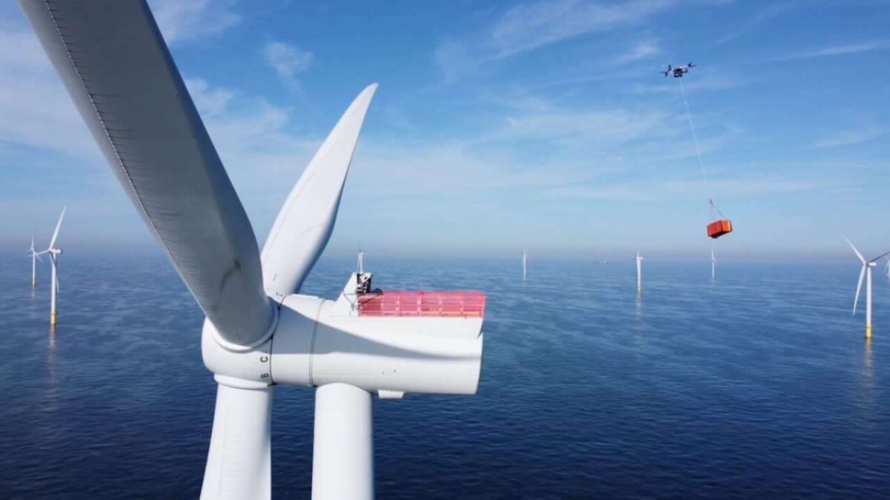 Drone flying near offshore wind farm turbines for inspection